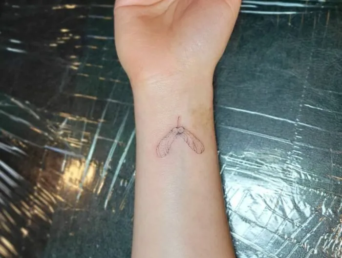 Minimalist tattoo of a seed pod on a wrist, simple and aesthetically pleasing to the eye.