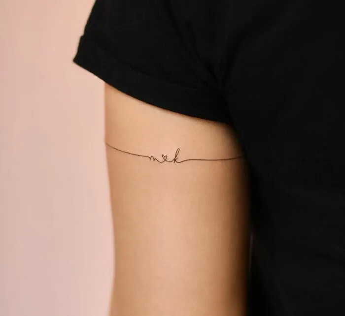 Minimalist tattoo on a person's arm with fine line work and a small heart design.