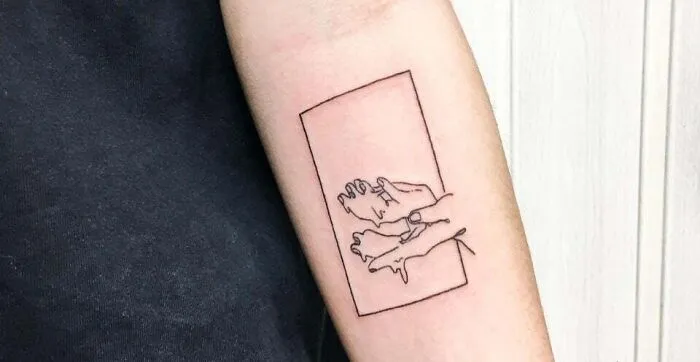 Minimal tattoo design of outlined hands within a rectangle on a person's forearm.