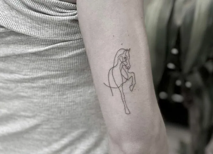 Single-line tattoo of a horse on an arm, showcasing fine-line perfection.