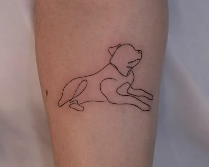 Single-line tattoo of a dog in fine-line style on a person's arm.