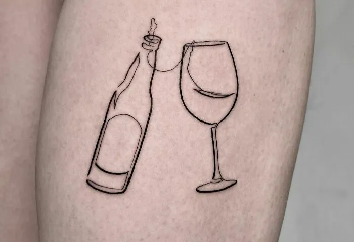Fine-line tattoo of a wine bottle and glass, drawn with a single line on skin.