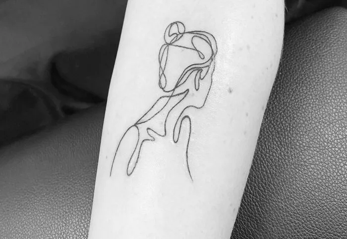 Fine-line single-line tattoo of a woman's silhouette on an arm.