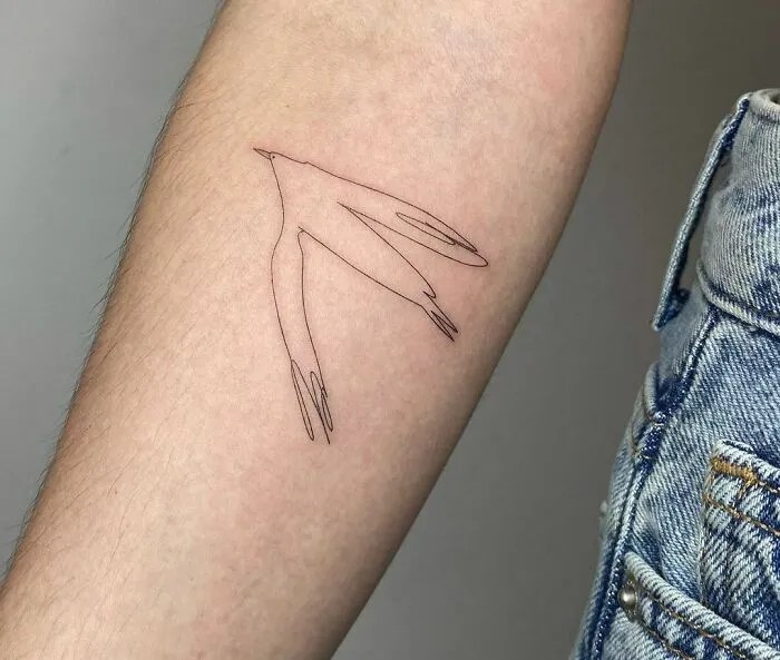 Fine-line single-line tattoo of a bird on a person's forearm, showcasing minimalist design.