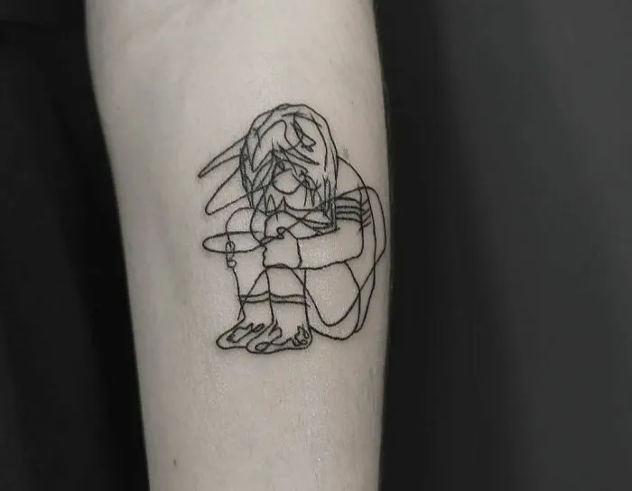 A single-line tattoo of a crouching figure, showcasing fine-line perfection on an arm.