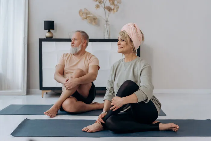 Woman and man doing exercises on a yoga mat 
