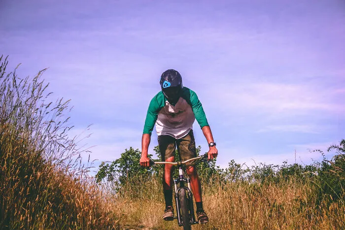 Man riding a bike in meadow with a helmet 