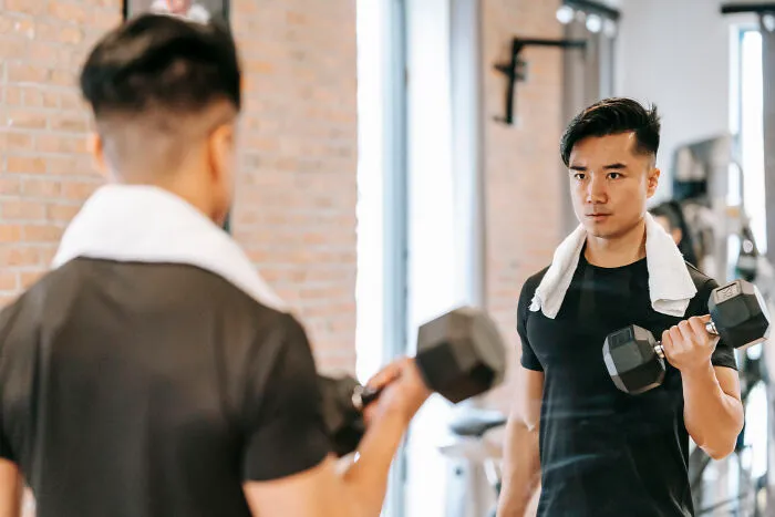 Man standing in front of the mirror and lifting a dumbbell  