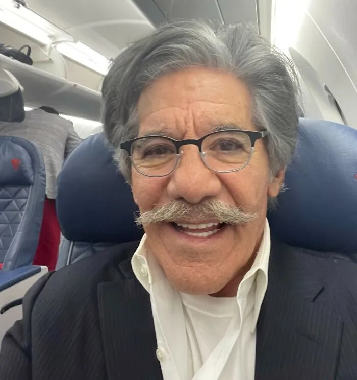 Geraldo Rivera wearing glasses and a suit, smiling on an airplane, representing famous people who got married multiple times.