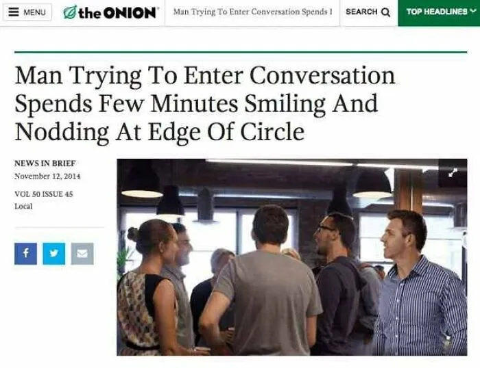 A group of people in conversation, one man with social anxiety stands smiling at the edge, hesitant to join in.
