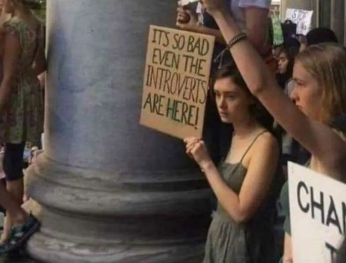 Person holding a sign about introverts at a protest, highlighting social anxiety.