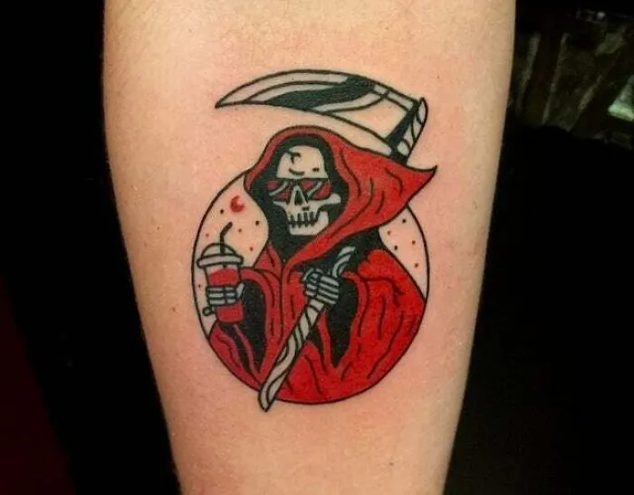 Trippy tattoo of a skeleton in a red hood with a scythe and drink on forearm.