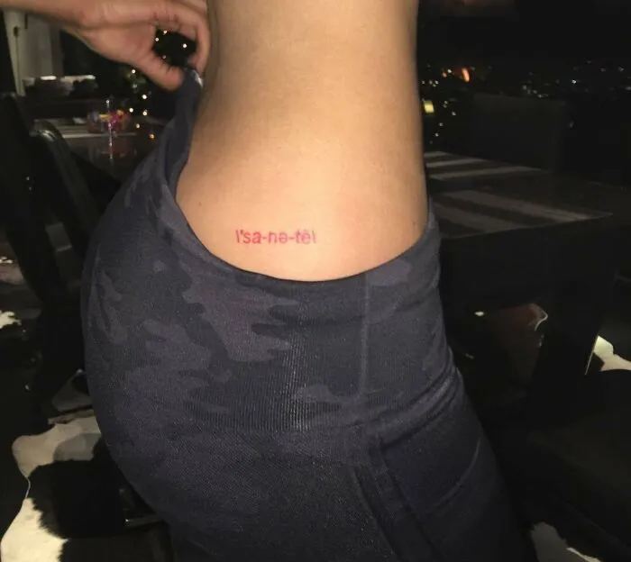Celebrity tattoo on a person's side, reading “l'sa-ne-tè,” shown in a close-up photo indoors.