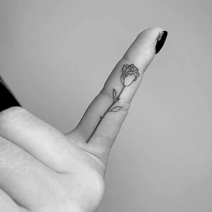 Minimalistic flower tattoo on a finger, representing celebrity tattoos.