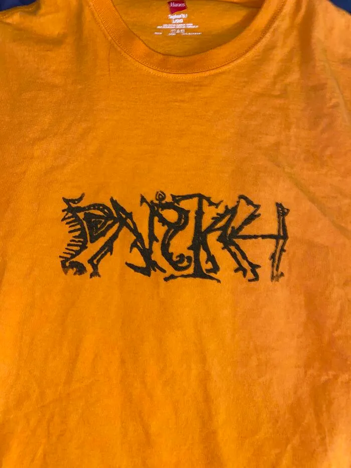 Me he comprado esta camiseta de segunda mano y necesito ayuda para identificar lo que pone o cualquier información sobre ella