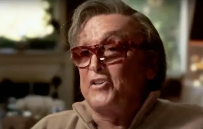Robert Evans wearing glasses and a beige jacket, featured among famous people who got married multiple times.