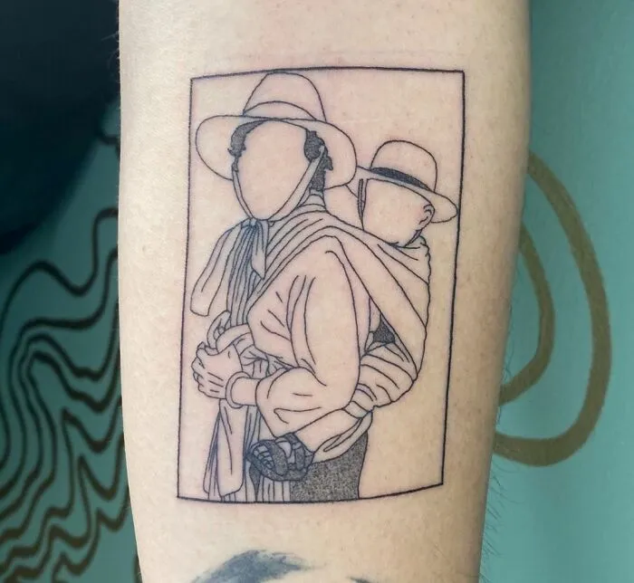 Minimalist tattoo of two faceless figures, one carrying a child in a sling, drawn with thin black lines.