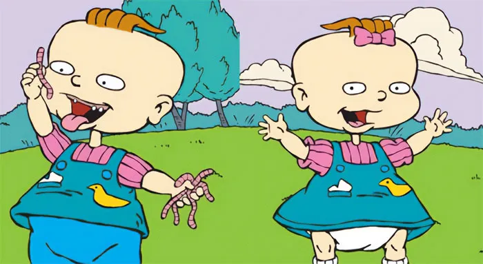 Cartoon couple of toddlers in a grassy field, both wearing blue outfits with ducks, showcasing playful expressions.