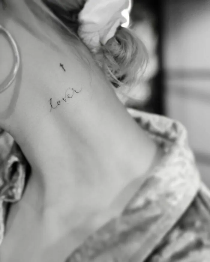 Neck tattoo of the word "lover" and a small cross, representing celebrity tattoos.