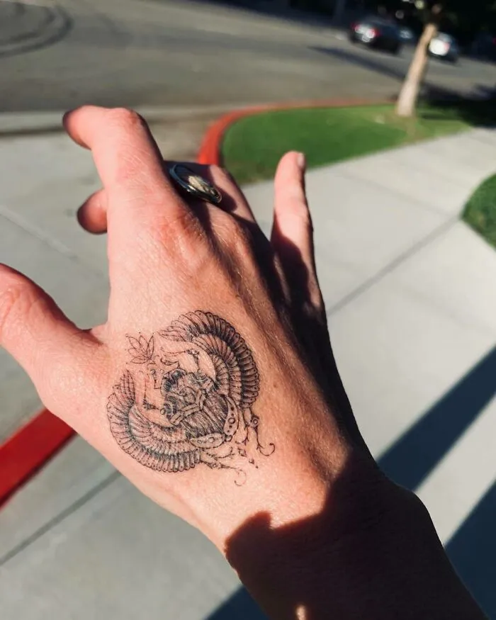 Hand displaying intricate ink art of a beetle tattoo, a recognizable celebrity tattoo design.