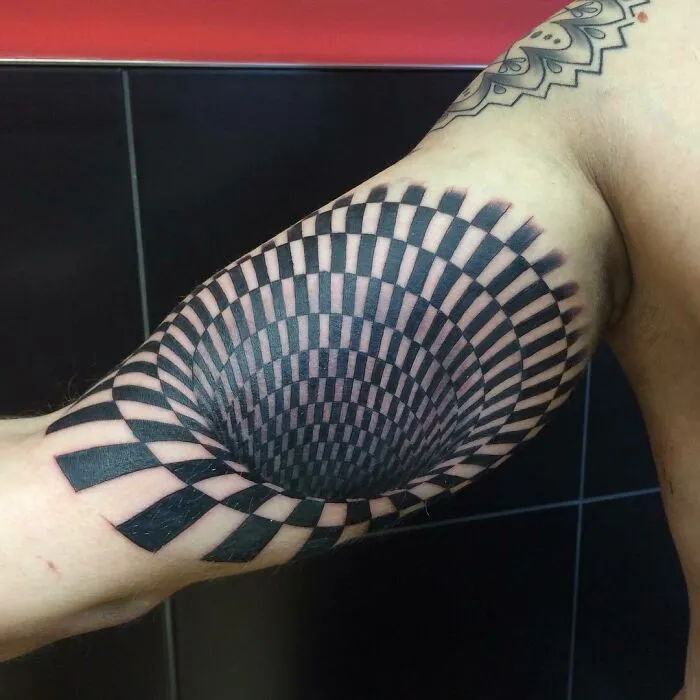 Optical illusion tattoo on arm, creating a 3D effect with a spiral design.