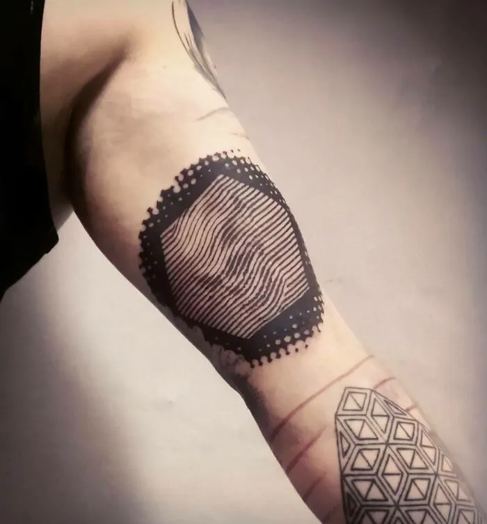 Arm with an optical illusion tattoo design featuring geometric shapes and lines.