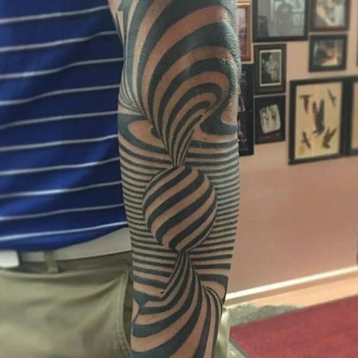 Optical illusion tattoo with stripes creating a 3D effect on a person's arm.