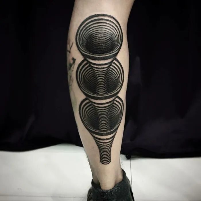 Optical illusion tattoo on calf with mind-bending design, featuring layered 3D circles creating a tunnel effect.