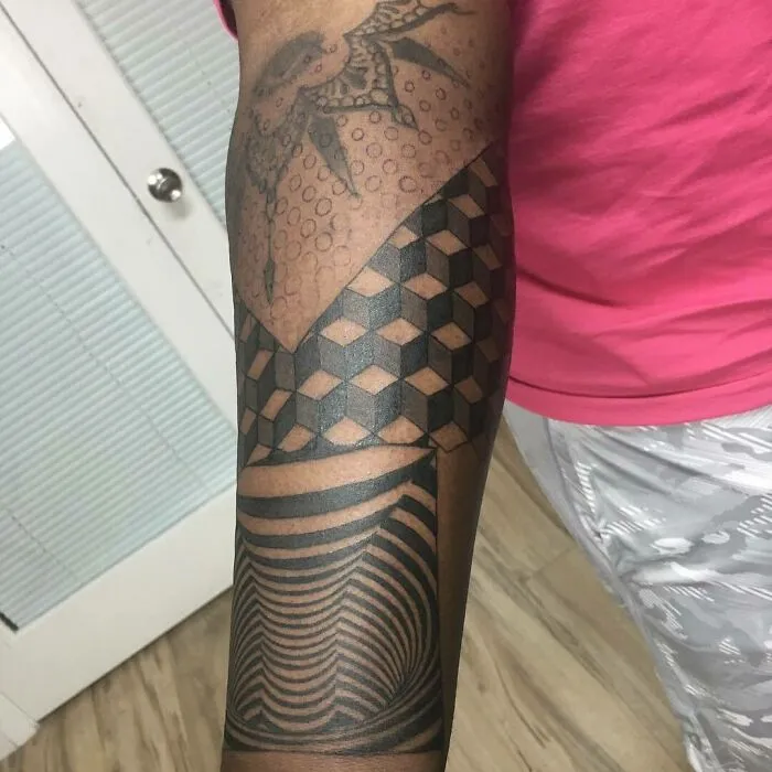 Optical illusion tattoo on arm with geometric patterns and intricate designs.