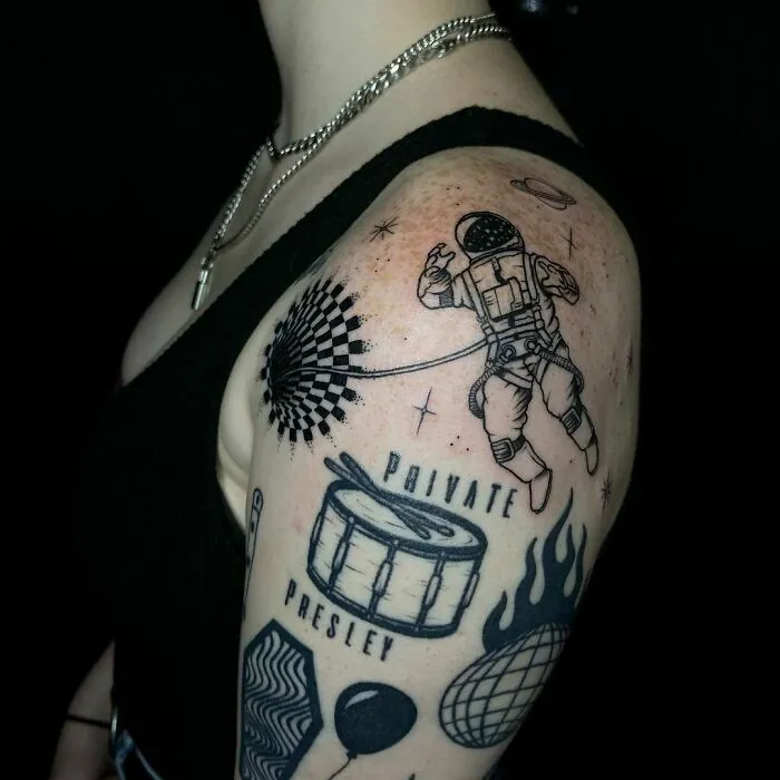 Astronaut optical illusion tattoo design on a person's upper arm, featuring various intricate elements.