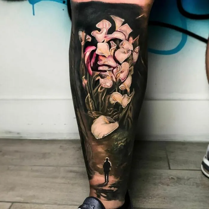 Optical illusion tattoo featuring flowers morphing into a woman's face, creating a mind-bending design on a leg.