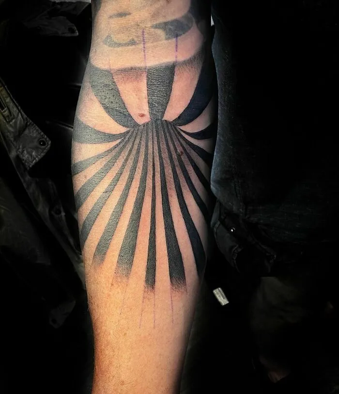 Optical illusion tattoo design on forearm with radiating black and gray lines creating a mesmerizing effect.