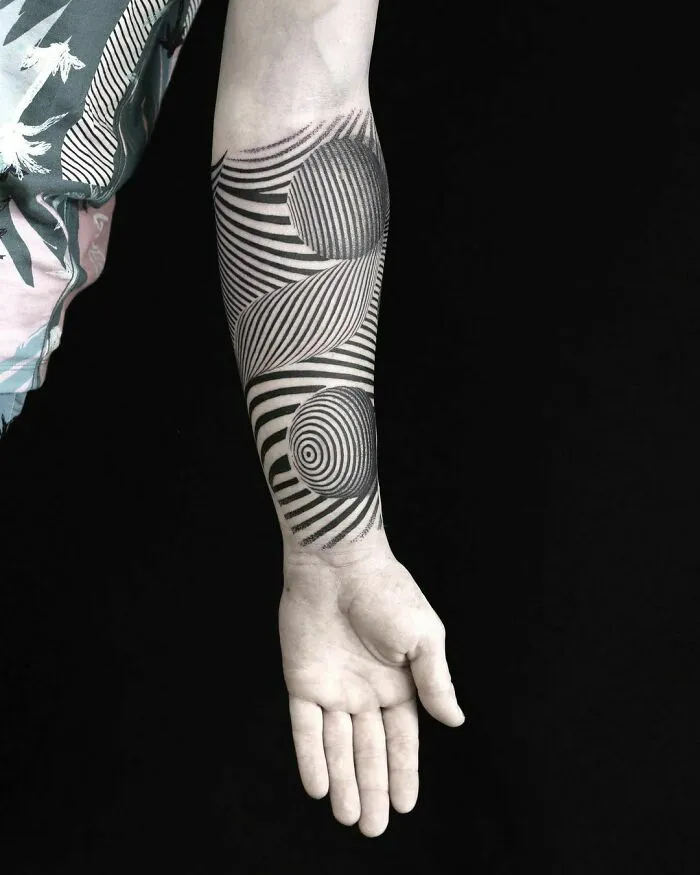 Arm with an optical illusion tattoo design featuring black and white swirls creating a 3D effect.