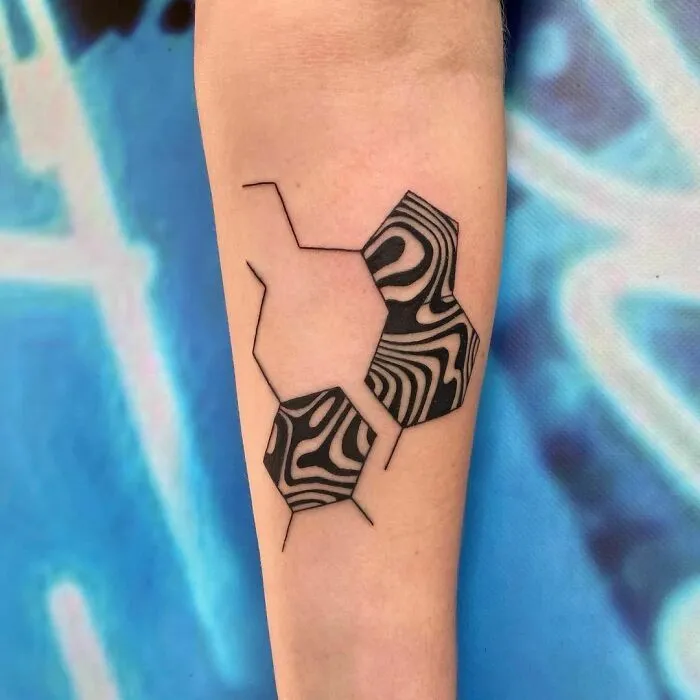Optical illusion tattoo with geometric shapes and mind-bending patterns on forearm.