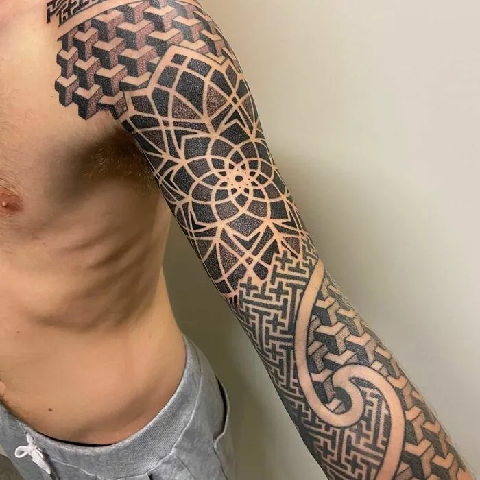 Intricate optical illusion tattoo sleeve with geometric, eye-bending patterns on a person's arm.
