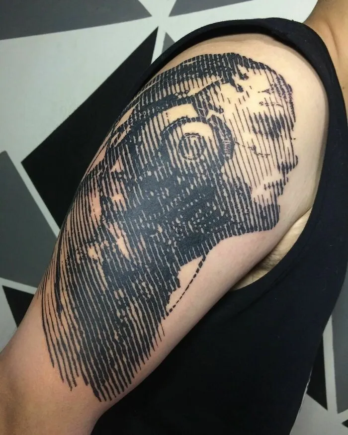Optical illusion tattoo of a face on an arm with mind-bending design lines.