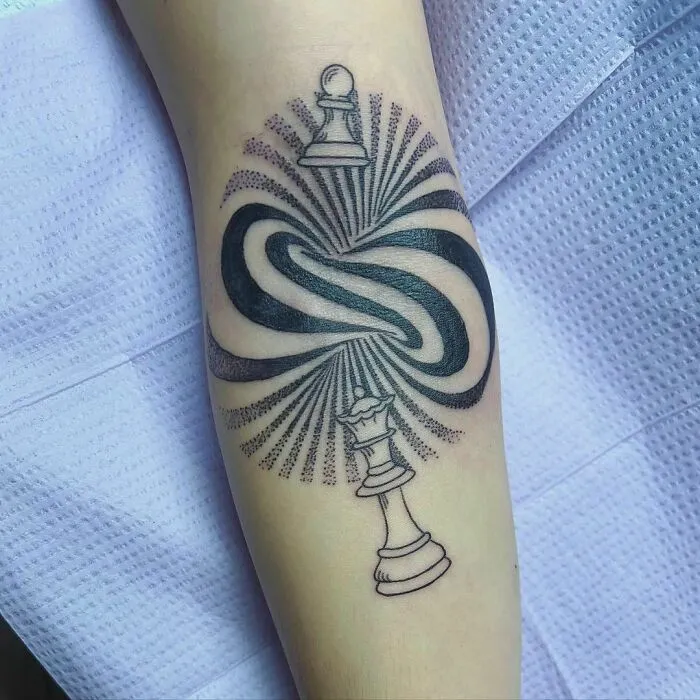 Optical illusion tattoo of chess pieces and swirling patterns on an arm, creating a mind-bending visual effect.