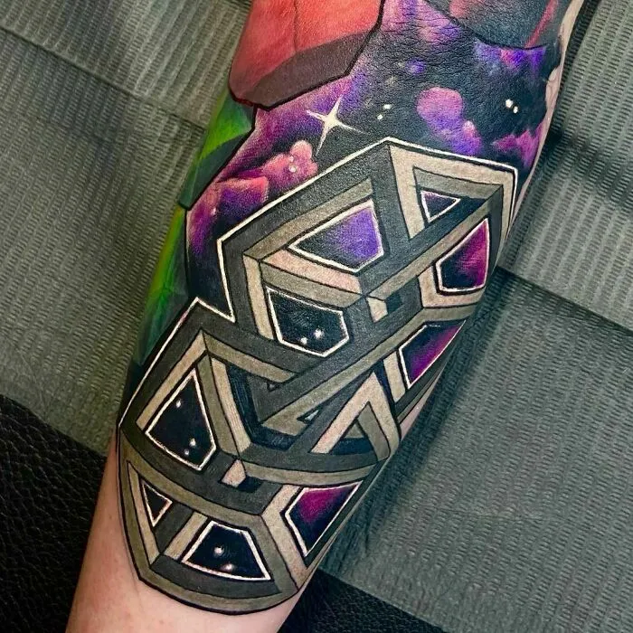 Optical illusion tattoo featuring geometric shapes and vibrant colors on an arm.