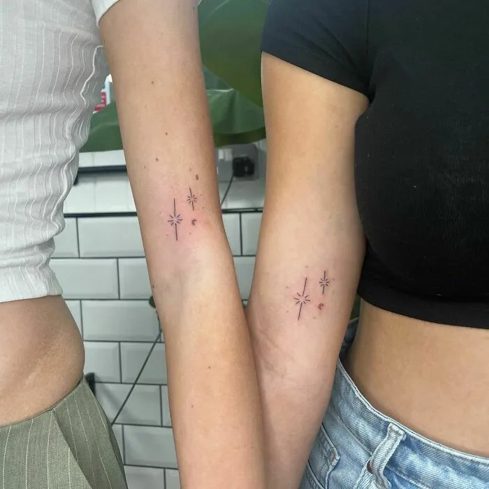 Minimalist tattoos of stars and dots on two forearms, showcasing aesthetically pleasing designs.