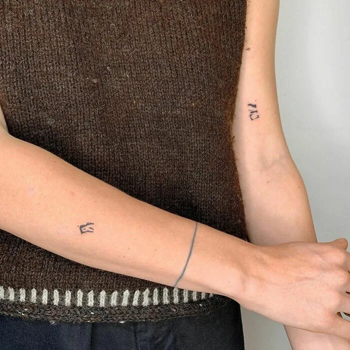 Minimalist tattoos on forearms, featuring small geometric shapes and lines, creating an aesthetically pleasing look.