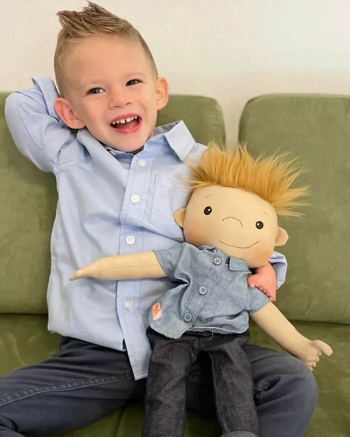 A happy boy hugging his custom doll, both with spiked hair, reflecting boy doll representation.