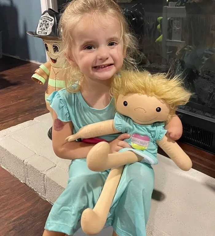 A young girl in pajamas happily hugs her custom doll representation with blonde hair, mirroring her features.