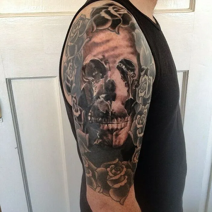 Optical illusion tattoo with roses and skull design on a person's arm.