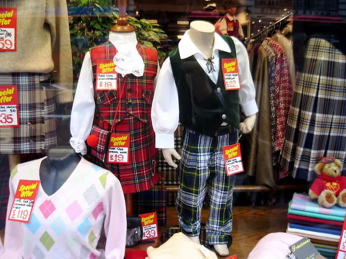 Children’s clothing displayed in a store window featuring various outfits with special offer price tags visible.