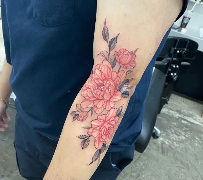 Arm tattoo featuring pink and black floral design in a psychedelic art style.
