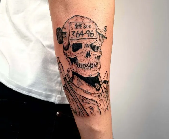 Tattoo of a grim skull with mechanical elements, showcasing psychedelic art on the forearm.