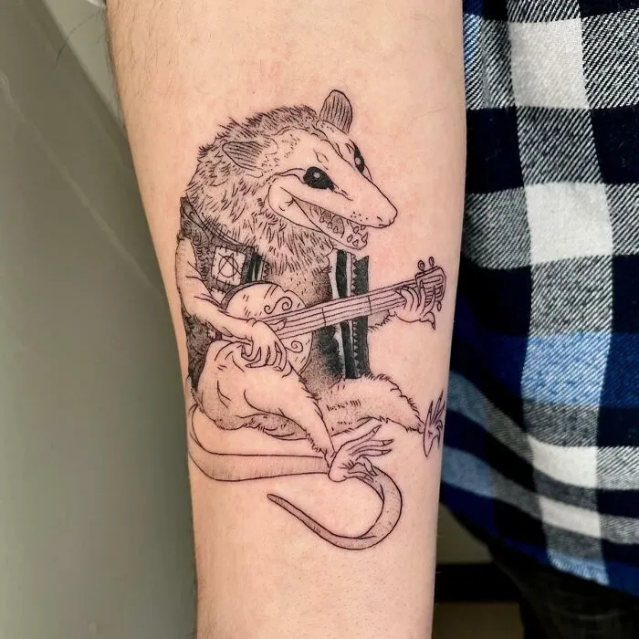 Tattoo of a rat playing a guitar, featuring psychedelic art style.