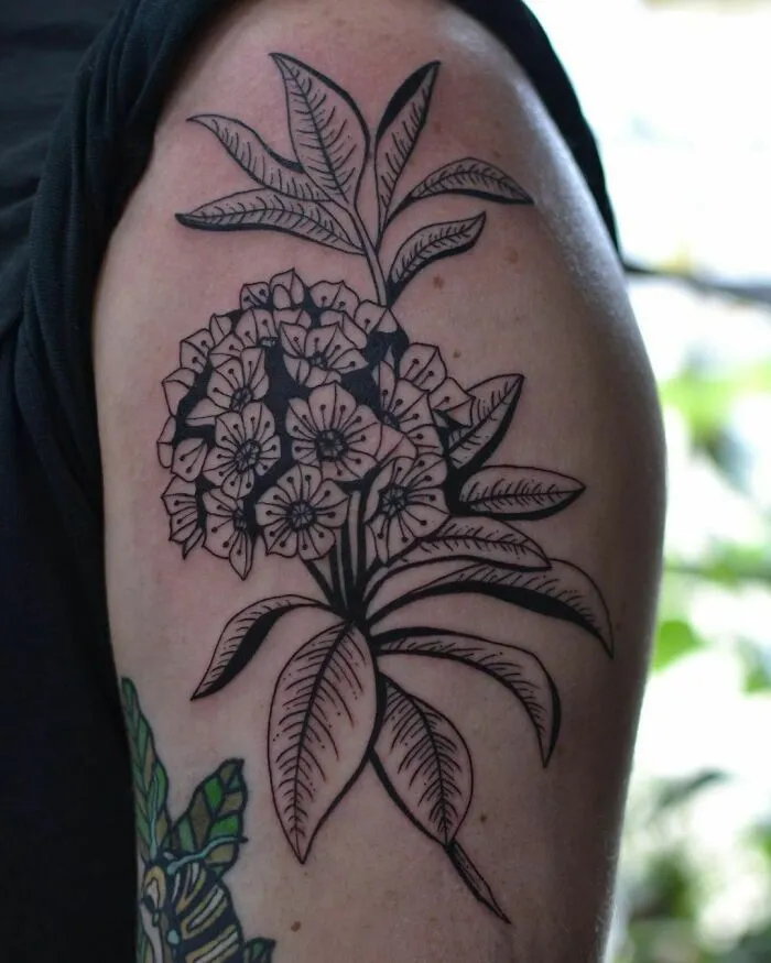 Nature tattoo featuring detailed black and grey floral design on upper arm.