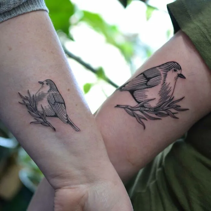 Two nature tattoos featuring birds on branches adorn forearms.
