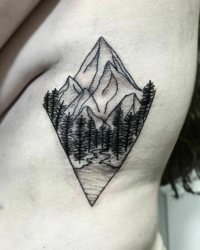 Nature tattoo design featuring mountains and pine trees in a geometric shape.